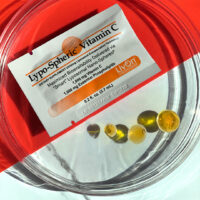 Liposomal vitamin C - Lypo-Spheric vitamin c sachet and goo on a glass plat, front view orange background